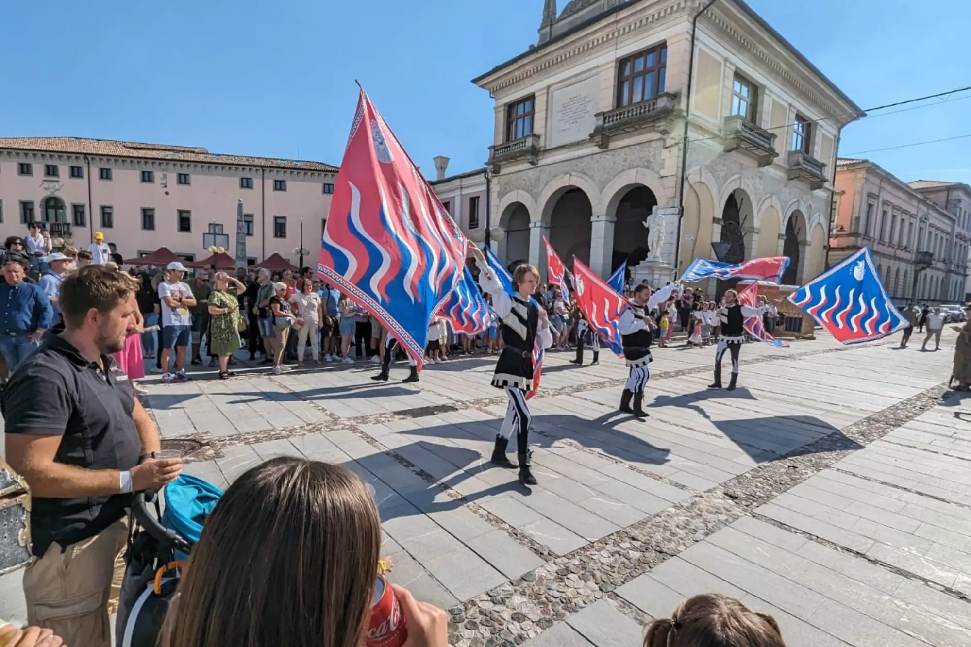 Rievocazione storica a Palmanova con sbandieratori in costume e bandiere medievali nella piazza centrale della città stellata.